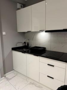 a white kitchen with a sink and white cabinets at Apartamenty Prestiż Podfigórna 200 metrów od centrum in Koszalin +61 photos