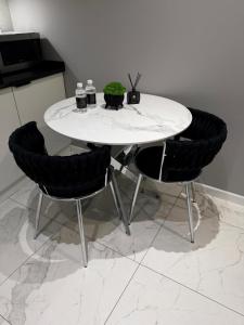 a white table with two chairs and two drinks on it at Apartamenty Prestiż Podfigórna 200 metrów od centrum in Koszalin