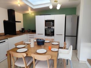 eine Küche mit einem Holztisch und Stühlen und eine Küche mit weißen Schränken in der Unterkunft L'ancienne Poste in Fort-Mahon-Plage