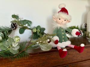 a small elf doll sitting on a shelf with christmas decorations at Sanderling House, walk to beach in Earnley