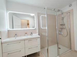 ein Badezimmer mit Waschbecken und Dusche mit Spiegel in der Unterkunft L'ancienne Poste in Fort-Mahon-Plage