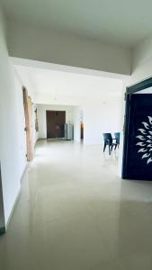 Newly built luxurious 4BHK near Tirupati Railway station في تيروباتي: غرفة بيضاء كبيرة ذات أرضية بيضاء وكرسي +صورتان