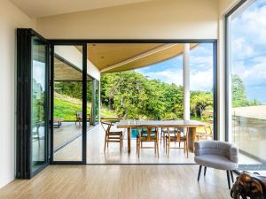 a dining room with glass doors and a table and chairs at Homey 2Br Villa Apricot Close to Beach Sea View in Plai Laem