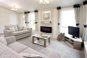 Una sala de estar con un sofá y un televisor. en Golden Sands Holiday Park, en Kinmel Bay
