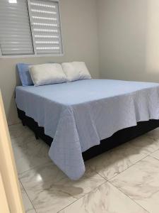 a bed with a blue blanket and two pillows at Apartamento in Espirito Santo Do Pinhal