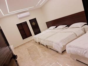 a bedroom with four beds with white sheets at Daftah Valley Farmhouse in Daftah
