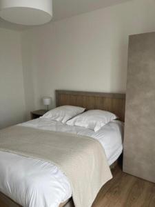 2 letti in una camera da letto con lenzuola e cuscini bianchi di Résidence de Brest Lambézellec a Brest