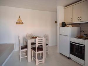 a kitchen with a table and chairs and a refrigerator at Moniasma Rustic Stone House in Folegandros in Ano Meria