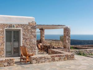 a stone house with a patio with a table and chairs at Moniasma Rustic Stone House in Folegandros in Ano Meria