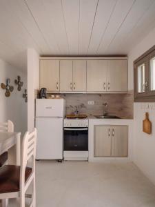 a kitchen with a white refrigerator and a stove at Moniasma Rustic Stone House in Folegandros in Ano Meria