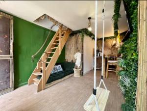 ein Wohnzimmer mit einer grünen Wand und einer Treppe in der Unterkunft Love room Évasion tropicale in Souppes-sur-Loing