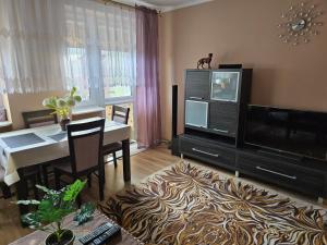 a living room with a dining table and a television at Centrum Jagoda in Pisz