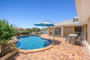 een zwembad met parasol naast een huis bij Waterfront entertainers dream with private beach in Gold Coast