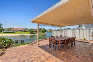 een houten tafel en stoelen onder een luifel op een terras bij Waterfront entertainers dream with private beach in Gold Coast