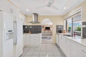 een keuken met witte kasten en een groot raam bij Waterfront entertainers dream with private beach in Gold Coast