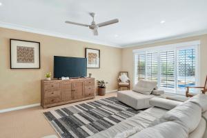 een woonkamer met een bank en een flatscreen-tv bij Waterfront entertainers dream with private beach in Gold Coast