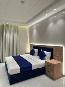 ein Schlafzimmer mit einem großen Bett und blauen Kissen in der Unterkunft شقق نطوان المفروشة in Abha