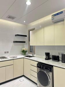 eine Küche mit weißen Schränken und einem Geschirrspüler in der Unterkunft شقق نطوان المفروشة in Abha