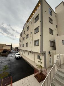 ein Gebäude mit einem auf einem Parkplatz geparkten Auto in der Unterkunft شقق نطوان المفروشة in Abha