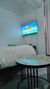 Una habitación con una cama, una mesa y un televisor. en Exciting, en Ongata Rongai 