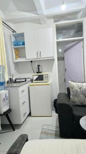 Una pequeña cocina con gabinetes blancos y un sofá. en Exciting, en Ongata Rongai 