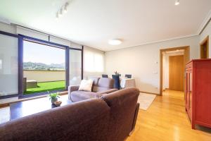 un soggiorno con un divano e una grande finestra di Apartamento Luz de Poniente a Llanes