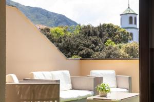 a patio with two white chairs and a lighthouse at Apto Llanes con Terraza y Jardín - Luz de Poniente in Llanes