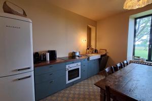 Una cocina con una mesa y un refrigerador blanco. en Paradis en Berry, en Le Pêchereau