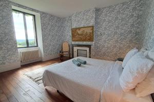 Un dormitorio con una cama blanca y una chimenea en Paradis en Berry, en Le Pêchereau