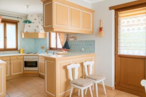 una cucina con mobili in legno e sedie bianche di Gîte le Platane a Montagnac