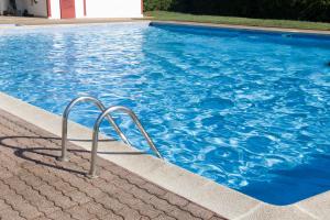 a swimming pool with blue water and metal rails at Cocon Madeleine Confort et piscine wifi et climatisation in Cayenne +18 photos