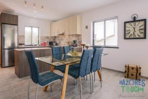 a kitchen and dining room with a glass table and chairs at Silver Gate Home in Cinco Ribeiras +12 photos