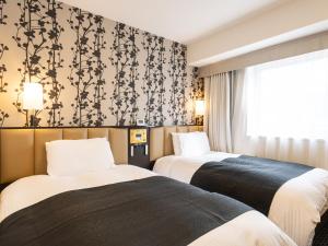 a hotel room with two beds and a window at APA Hotel Kanazawa Chuo in Kanazawa