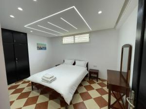 Maison Bord de Mer Skhirate في الصخيرات‎: غرفة نوم بسرير وملاءات بيضاء وطاولة