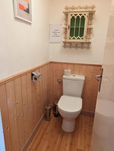 a bathroom with a toilet with wood paneling and a window at Chambre 3, Le clos du Ru in Presnoy