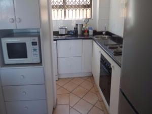 a small kitchen with a microwave and a sink at Villa Siesta Flat No 5 in Margate