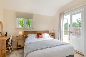 The Bolthole and Warren في Biddenden: غرفة نوم بها سرير ومكتب ونافذة