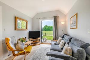 The Bolthole and Warren في Biddenden: غرفة معيشة مع أريكة وتلفزيون