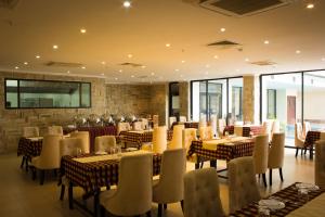 uma sala de jantar com mesas, cadeiras e janelas em Seashells Millennium Hotel em Dar es Salaam