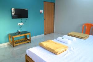 Un dormitorio con dos camas y un televisor en la pared. en Lake Breeze Resort, en Alibaug