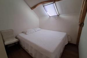 a small bedroom with a white bed and a window at La bergerie - Point de vue sur la Creuse in Ceaulmont +3 photos