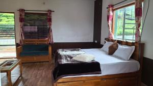 a bedroom with a bed and a chair and a window at Greenary homestay in Ooty