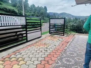 a person standing next to a gate on a road at Greenary homestay in Ooty
