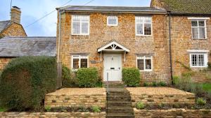 een oud bakstenen huis met een witte deur bij Oak Cottage in Swerford
