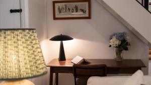 een kamer met een bureau met een lamp en een tafel met een stoel bij Oak Cottage in Swerford +17 foto's