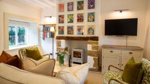 een woonkamer met open haard en tv bij Oak Cottage in Swerford