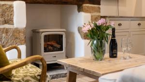 een tafel met een vaas met bloemen en een open haard bij Oak Cottage in Swerford