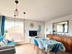 sala de estar con mesa con sillas y TV en Brise Marine - Appartement 2 chambres avec balcon, vue mer & parking privé à 30 m de la plage, en Palavas-les-Flots