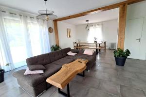 a living room with a couch and a wooden table at Les hauts du lac - 500 m du lac - Vu sur le lac in Éguzon-Chantôme