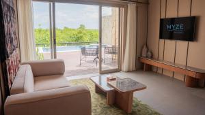 a living room with a couch and a table and a balcony at Myze Hotel Waingapu in Waingapu